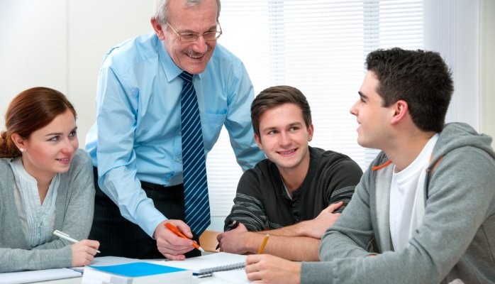 An educator working with a small group of young adult learners around a table