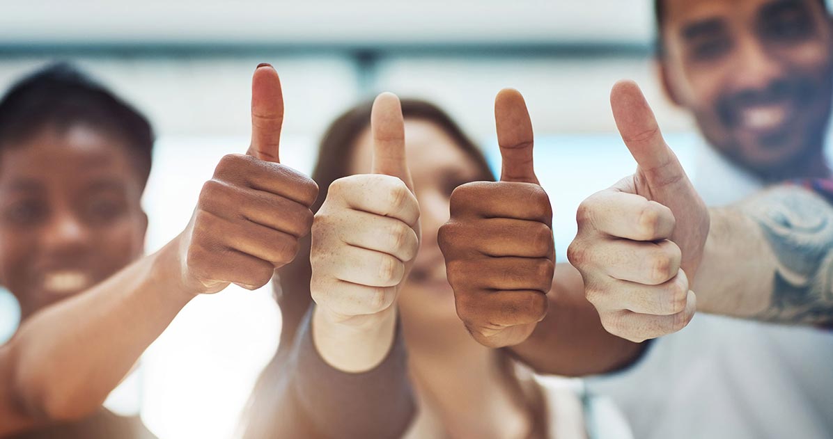 A diverse group of people raising their hands in a thumbs-up gesture together