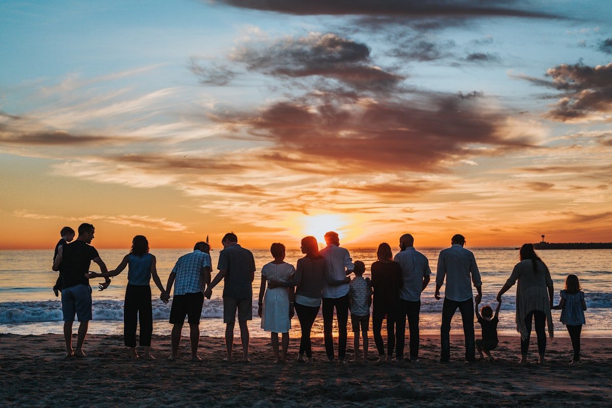 An extended family standing together outdoors at sunset
