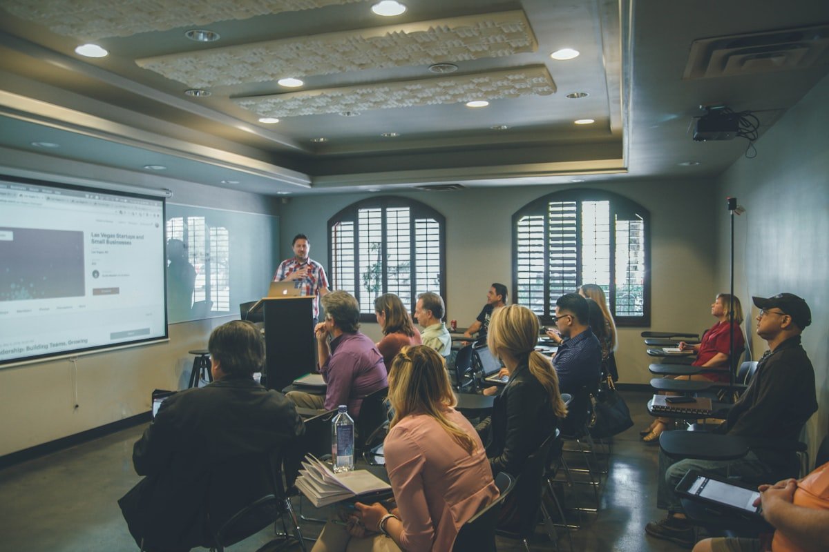An instructor presenting to a seated group of young adults in a training room