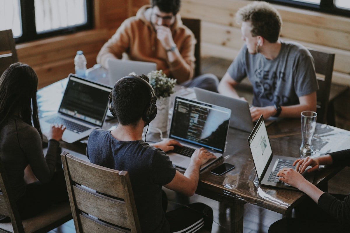 A team of four collaborating over laptops in a warm, informal workspace